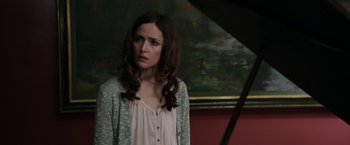 Movie still from “Insidious: Chapter 2” (2013), directed by James Wan – A woman standing in front of a piano in front of a painting; Medium shot, Over the shoulder angle