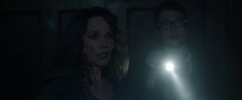 Movie still from “Insidious: Chapter 2” (2013), directed by James Wan – A woman is looking at the camera while a man is holding a flashlight; Close Up shot, Over the shoulder angle