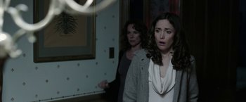 Movie still from “Insidious: Chapter 2” (2013), directed by James Wan – Two women standing in front of a mirror in a dark room; Medium shot, Over the shoulder angle