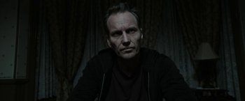 Movie still from “Insidious: Chapter 2” (2013), directed by James Wan – A person sitting in a room; Close Up shot, Low angle