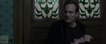 Movie still from “Insidious: Chapter 2” (2013), directed by James Wan – A man sitting in front of a stained - glass window; Close Up shot, Over the shoulder angle