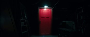 Movie still from “Insidious: Chapter 2” (2013), directed by James Wan – A red door in a dark room lit by a lamp; Wide shot, High angle
