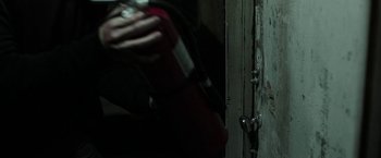 Movie still from “Insidious: Chapter 2” (2013), directed by James Wan – A person holding a fire extinguisher next to an open door; Extreme Close Up shot, High angle