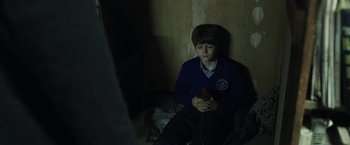 Movie still from “Insidious: Chapter 2” (2013), directed by James Wan – A young boy sitting on the floor looking at a cell phone; Medium shot, High angle