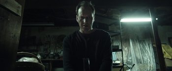 Movie still from “Insidious: Chapter 2” (2013), directed by James Wan – A man in a black shirt is holding a knife; Medium shot, Low angle