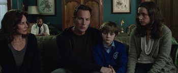 Movie still from “Insidious: Chapter 2” (2013), directed by James Wan – A man and a boy sitting on a couch together; Medium shot, Over the shoulder angle