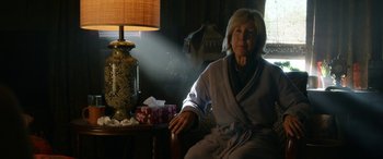 Movie still from “Insidious: Chapter 3” (2015), directed by Leigh Whannell – An older woman sitting on a chair in front of a lamp; Medium shot, Low angle