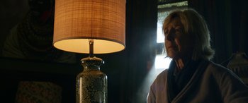 Movie still from “Insidious: Chapter 3” (2015), directed by Leigh Whannell – A woman standing in front of a lamp in a dark room; Close Up shot, Low angle