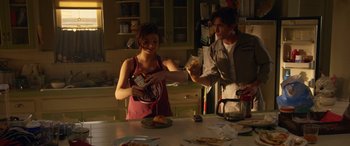 Movie still from “Insidious: Chapter 3” (2015), directed by Leigh Whannell – A woman is holding a can of soda and a man is holding a piece of pizza; Medium shot, Over the shoulder angle