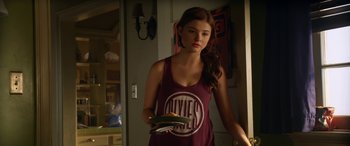 Movie still from “Insidious: Chapter 3” (2015), directed by Leigh Whannell – A woman in a red shirt holding a pair of shoes; Medium shot, Over the shoulder angle