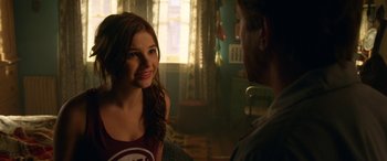 Movie still from “Insidious: Chapter 3” (2015), directed by Leigh Whannell – A young woman smiling at a man in a room; Close Up shot, Over the shoulder angle