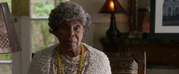 Movie still from “Insidious: Chapter 3” (2015), directed by Leigh Whannell – An older woman wearing a yellow necklace and a white sweater; Close Up shot, Over the shoulder angle