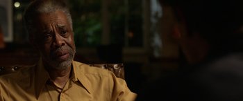 Movie still from “Insidious: Chapter 3” (2015), directed by Leigh Whannell – An older man wearing a yellow shirt sitting in a chair; Close Up shot, Over the shoulder angle