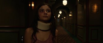 Movie still from “Insidious: Chapter 3” (2015), directed by Leigh Whannell – A woman wearing a neck brace stands in a hallway; Close Up shot, Over the shoulder angle