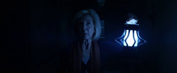 Movie still from “Insidious: Chapter 3” (2015), directed by Leigh Whannell – An older woman is standing in a dark room; Close Up shot, Low angle