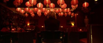 Movie still from “Insidious: Chapter 3” (2015), directed by Leigh Whannell – A woman sitting in a chair in front of red lanterns; Wide shot, Over the shoulder angle