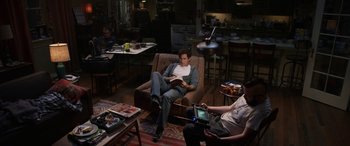Movie still from “Insidious: Chapter 3” (2015), directed by Leigh Whannell – A man sitting on a brown couch in a living room; Wide shot, High angle