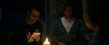 Movie still from “Insidious: Chapter 3” (2015), directed by Leigh Whannell – Two men sitting in front of a lit candle; Medium shot, Over the shoulder angle