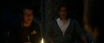 Movie still from “Insidious: Chapter 3” (2015), directed by Leigh Whannell – Two men standing in front of a lit candle in a dark room; Medium shot, Over the shoulder angle