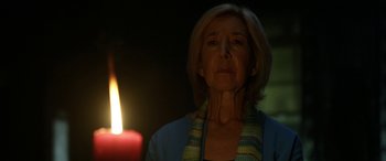 Movie still from “Insidious: Chapter 3” (2015), directed by Leigh Whannell – A woman standing in front of a lit candle in the dark; Close Up shot, Low angle