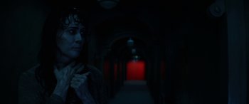 Movie still from “Insidious: Chapter 3” (2015), directed by Leigh Whannell – A woman standing in a dark hallway next to a red door; Close Up shot, Over the shoulder angle