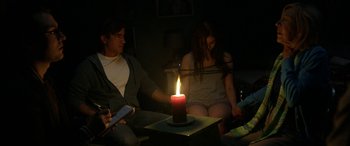 Movie still from “Insidious: Chapter 3” (2015), directed by Leigh Whannell – Two people sitting in a room with a lit candle; Medium shot, High angle
