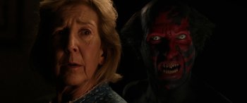 Movie still from “Insidious: Chapter 3” (2015), directed by Leigh Whannell – An old woman and a demon face in a dark room; Close Up shot, Over the shoulder angle