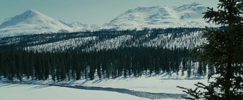 Movie still from “Into the Wild” (2007), directed by Sean Penn – A view of a snowy mountain with trees in the background; Extreme Wide shot, High angle