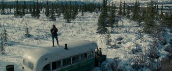 Movie still from “Into the Wild” (2007), directed by Sean Penn – A man standing on top of a bus in the snow; Extreme Wide shot, High angle