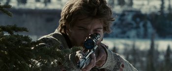 Movie still from “Into the Wild” (2007), directed by Sean Penn – A man is holding a rifle and looking through the scope; Close Up shot, Over the shoulder angle