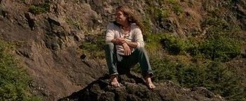 Movie still from “Into the Wild” (2007), directed by Sean Penn – A woman sitting on a rock with her hands on her knees; Medium shot, Low angle
