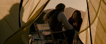 Movie still from “Into the Wild” (2007), directed by Sean Penn – A group of people sitting on a chair next to a body of water; Medium shot, Over the shoulder angle
