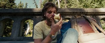 Movie still from “Into the Wild” (2007), directed by Sean Penn – A man eating a hot dog on top of a bun; Medium shot, Low angle