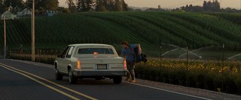 Movie still from “Into the Wild” (2007), directed by Sean Penn – A man standing on the side of a road next to a car; Wide shot, Over the shoulder angle