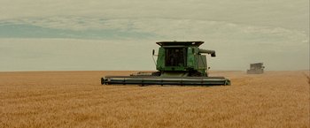 Movie still from “Into the Wild” (2007), directed by Sean Penn – A green tractor is in the middle of a wheat field; Extreme Wide shot, High angle