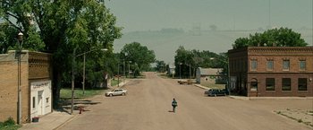 Movie still from “Into the Wild” (2007), directed by Sean Penn – A person riding a skate board on a street; Extreme Wide shot, High angle