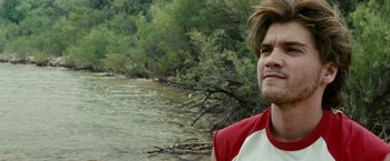 Movie still from “Into the Wild” (2007), directed by Sean Penn – A man standing next to a body of water; Close Up shot, Over the shoulder angle
