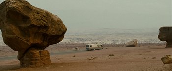 Movie still from “Into the Wild” (2007), directed by Sean Penn – An rv traveling down a road in the middle of the desert; Extreme Wide shot, High angle