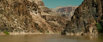 Movie still from “Into the Wild” (2007), directed by Sean Penn – A boat in the middle of a river near a mountain; Extreme Wide shot, High angle
