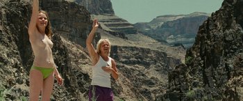 Movie still from “Into the Wild” (2007), directed by Sean Penn – A man standing on top of a mountain holding his hands up; Wide shot, Low angle