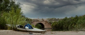 Movie still from “Into the Wild” (2007), directed by Sean Penn – A person walking across a bridge over a body of water; Extreme Wide shot, Over the shoulder angle