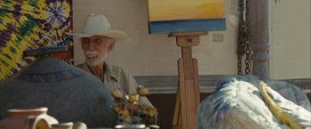Movie still from “Into the Wild” (2007), directed by Sean Penn – An older man sitting in front of a painting; Close Up shot, Over the shoulder angle