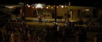 Movie still from “Into the Wild” (2007), directed by Sean Penn – A man playing a guitar in front of a group of onlookers; Extreme Wide shot, High angle