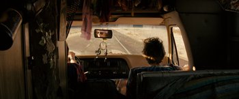 Movie still from “Into the Wild” (2007), directed by Sean Penn – A man driving a car on a road; Wide shot, Over the shoulder angle