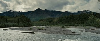 Movie still from “Into the Wild” (2007), directed by Sean Penn – A person standing on a rock in a river; Extreme Wide shot, High angle