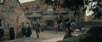 Movie still from “Into the Woods” (2014), directed by Rob Marshall – A group of people walking in front of a building; Wide shot, Low angle