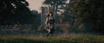 Movie still from “Into the Woods” (2014), directed by Rob Marshall – A woman is running through a field with a castle in the background; Wide shot, Low angle