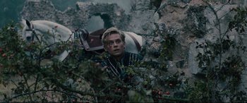 Movie still from “Into the Woods” (2014), directed by Rob Marshall – A man in black jacket looking over a rock wall; Medium shot, Low angle