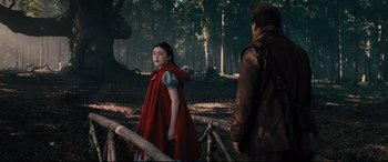 Movie still from “Into the Woods” (2014), directed by Rob Marshall – A woman in a red dress standing next to a man in a forest; Wide shot, Over the shoulder angle