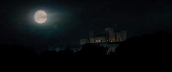 Movie still from “Into the Woods” (2014), directed by Rob Marshall – A castle is lit up at night in the dark; Extreme Wide shot, Low angle